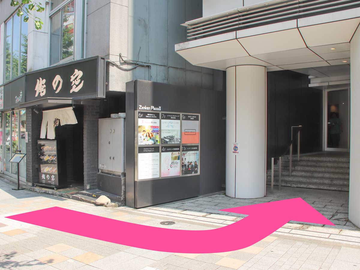 Left-pointing arrow directing visitors to Zenken Plaza II entrance for Sakura Mobile Shinjuku.